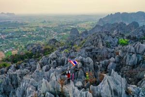 two people standing on top of a mountain with a kite at เจอาร์รีสอร์ท ที่พักบ้านมุงเนินมะปราง in Ban Mung