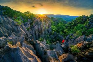 a person standing on top of a mountain at sunset at เจอาร์รีสอร์ท ที่พักบ้านมุงเนินมะปราง in Ban Mung