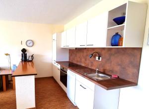 a kitchen with white cabinets and a sink at Boddenhof Apartment 48 - Terrasse für Hundefreunde in Buschvitz +10 photos