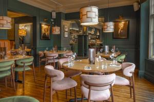 a restaurant with tables and chairs in a room with green walls at The Wheatsheaf Hotel, Sandbach in Sandbach