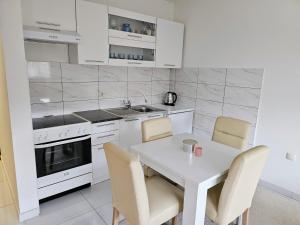 a white kitchen with a white table and chairs at Apartman Sunce in Bosanska Gradiška