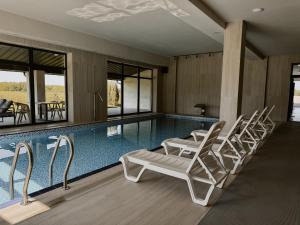 a swimming pool with white lounge chairs next to it at Готель з басейном та сауною Горинський in Ryasniki