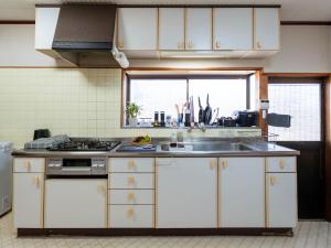 a kitchen with white cabinets and a sink and a window at Guesthouse NAMAZU in Anan