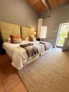 a bedroom with two beds and a large window at Soeterus Guest Farm in Calitzdorp
