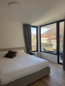 a bedroom with a bed and a large window at Live Lugano - Via Muggina in Viganello