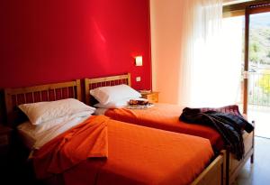 two beds in a room with a red wall at Hotel Ristorante Daino in Pietramurata