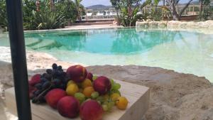 a pile of fruit sitting on a table next to a swimming pool at Oasi conca d'oro glamping in Noto