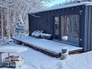 a snow covered yard with a cabin in the woods at Модрина Космач ko kosmach in Kozmacz