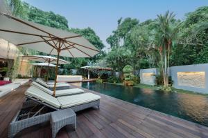 two lounge chairs and an umbrella next to a swimming pool at The Muse Luxury Eco-Living in Munggu