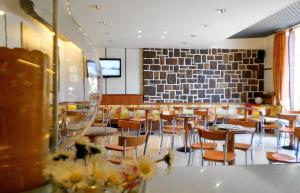 a restaurant with tables and chairs and a brick wall at Hotel Ristorante Daino in Pietramurata