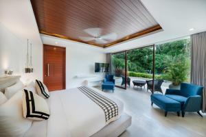 a bedroom with a white bed and blue chairs at The Muse Luxury Eco-Living in Munggu