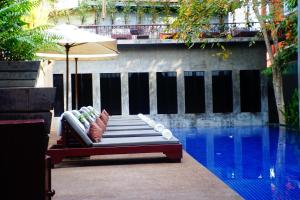 a bench with an umbrella next to a swimming pool at Golden Temple Villa in Siem Reap
