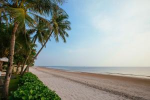 a sandy beach with palm trees and the ocean at Cape Nidhra Hotel in Hua Hin