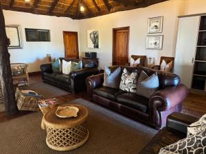 a living room with leather couches and a table at Knysna Elephant Park Lodge in Plettenberg Bay