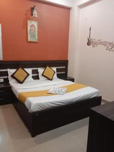 a bedroom with a bed with a orange wall at Hotel Ganges Park in Haridwār