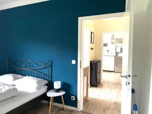 a bedroom with a blue wall and a bed and a stool at City Wohnung in Haltern gratis Parken, Netflix & Wäschepaket in Haltern +5 photos