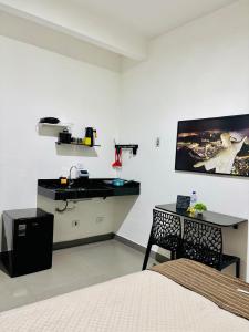 a bedroom with a bed and a desk and a sink at VOER - BR Flat Hospedaria in Sete Lagoas