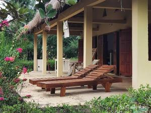a group of wooden benches on a porch of a house at Baobab Beach Villa in Abémé