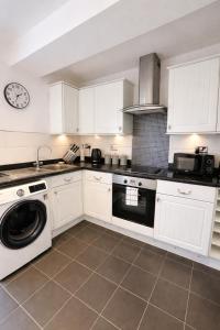 a kitchen with white cabinets and a washing machine at Parkfield House in Smethwick