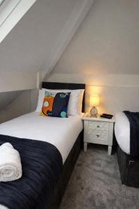 a bedroom with two beds and a table with a lamp at Parkfield House in Smethwick