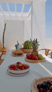 a table with plates of fruit in baskets on it at Seapalm Villa - Elegant Stay - Steps from the Sea in Lachania