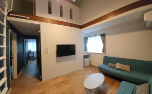 a living room with a couch and a tv at Pension Green Lake in Gujo