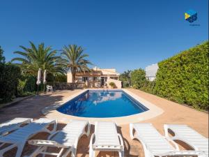 a swimming pool with white lounge chairs and a house at Can Moragues and Martorell in Badia Blava