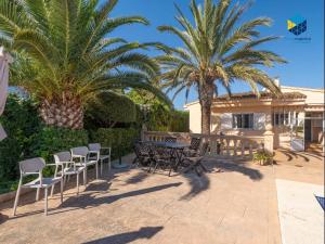 a patio with chairs and a table and palm trees at Can Moragues and Martorell in Badia Blava