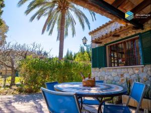 a table and chairs on a patio with a palm tree at Can Moreu in Caimari