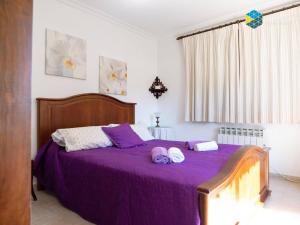 a bedroom with a purple bed with two towels on it at Can Moreu in Caimari