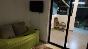 a living room with a green couch and a television at Chacrinha in Campinas