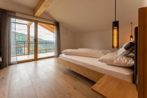 a bedroom with two beds and a large window at Gasthof Videgg in Schenna