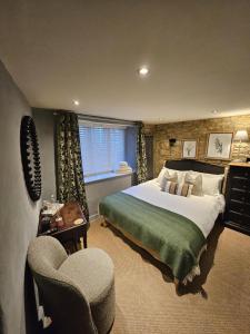 a bedroom with a large bed and a chair at Cotswold Cottage Guest House in Stow on the Wold