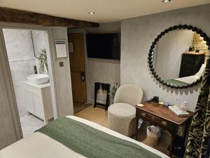 a bedroom with a bed and a mirror and a sink at Cotswold Cottage Guest House in Stow on the Wold