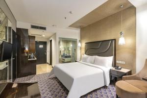 a bedroom with a large white bed and a bathroom at Fairview Hotel by ARTOTEL in Jakarta +22 photos