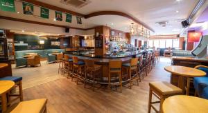 a bar in a restaurant with wooden tables and chairs at Hibernian Hotel & Leisure Centre in Mallow