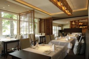 a restaurant with white tables and chairs and windows at Rebers Pflug in Schwäbisch Hall