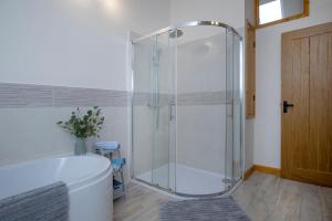 a shower with a glass door in a bathroom at Bamford Barn in Ottery Saint Mary +16 photos