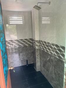 a bathroom with a shower with black and white tiles at Chandani Hostel in Galle