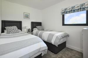 a bedroom with two beds and a window at 2 Bed in Abererch oc-glwysf in Abererch
