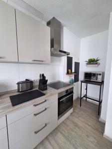 a kitchen with white cabinets and a sink and a stove at Ferienwohnung NR1 in Großräschen +9 photos