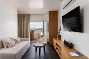 ein Wohnzimmer mit Sofa und Flachbildfernseher in der Unterkunft Mykonos Kosmoplaz Beach Resort Hotel in Platis Gialos