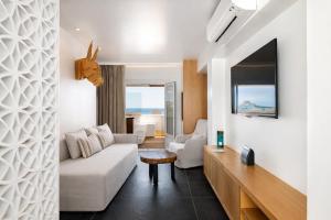ein Wohnzimmer mit einem weißen Sofa und einem Tisch in der Unterkunft Mykonos Kosmoplaz Beach Resort Hotel in Platis Gialos + 90 Fotos