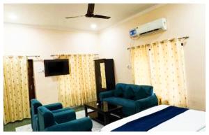 a bedroom with blue chairs and a bed and a tv at Hotel Indra Palace Jaunpur in Jaunpur