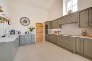 a kitchen with gray cabinets and a clock on the wall at 3 Bed in Trawsfynydd oc-wag718 in Trawsfynydd