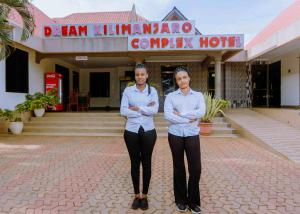 two women standing in front of a building with their arms crossed at Dream Kilimanjaro Complex Hotel in Msaranga