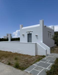 a white house with a white fence at Iosub Houses & Studios - Beach House in Koumbara in Tzamaria
