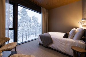 a bedroom with a bed and a large window at Gáldu Hotel & Spa in Saariselka