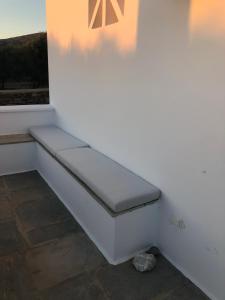 a white bench sitting on a wall next to a window at Iosub Houses & Studios - Beach House in Koumbara in Tzamaria