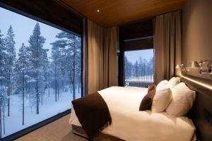 a bedroom with a bed and a large window at Gáldu Hotel & Spa in Saariselka